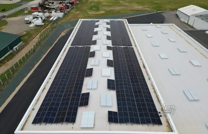 Vue drone d'un bâtiment industriel à toit plat, deux longues rangées de panneaux